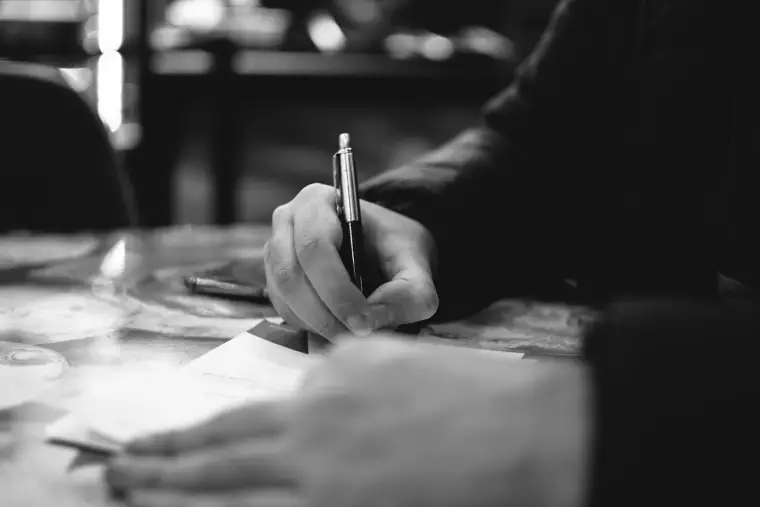 A pen held mid-signature over a page