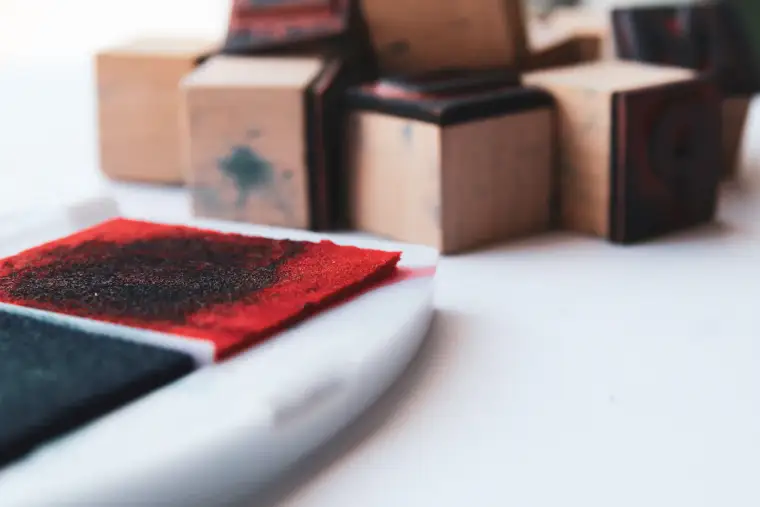 A red ink pad beside wooden stamps