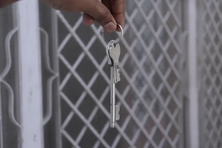 A hand turning a key in the security gate of a South African home